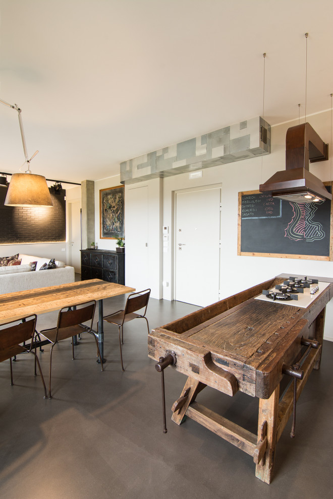 Photo of a mid-sized industrial galley open plan kitchen in Florence with a farmhouse sink, raised-panel cabinets, grey cabinets, concrete benchtops, grey splashback, cement tile splashback, stainless steel appliances, concrete floors, with island and grey benchtop.