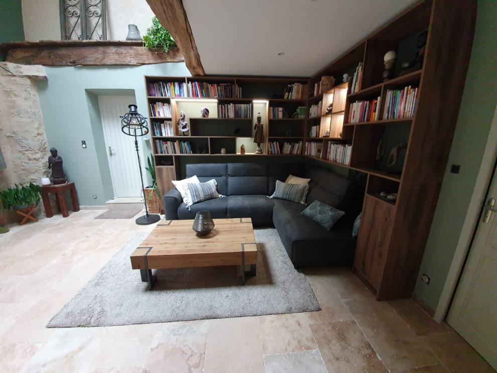 Foto di un soggiorno stile loft con libreria, pareti verdi, pavimento in travertino, TV a parete, pavimento beige e travi a vista