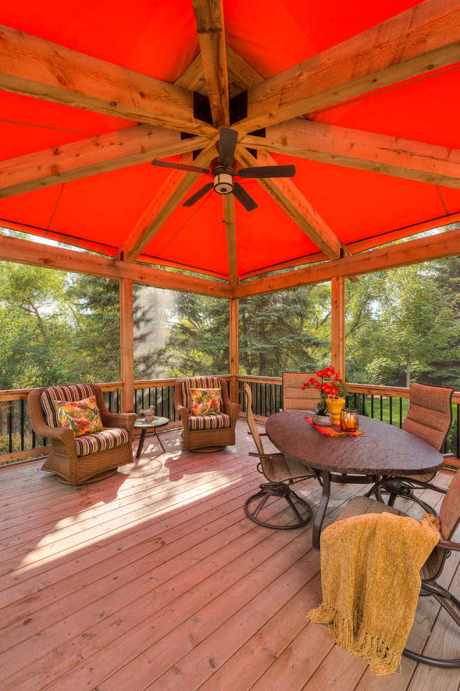 This is an example of a large transitional backyard deck in Minneapolis with an awning.