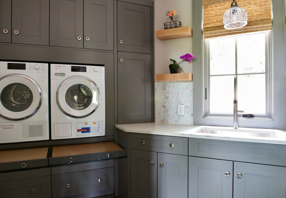 Small contemporary l-shaped dedicated laundry room in Other with recessed-panel cabinets, grey cabinets, quartz benchtops, multi-coloured splashback, glass tile splashback, white walls, ceramic floors, a side-by-side washer and dryer, grey floor and white benchtop.