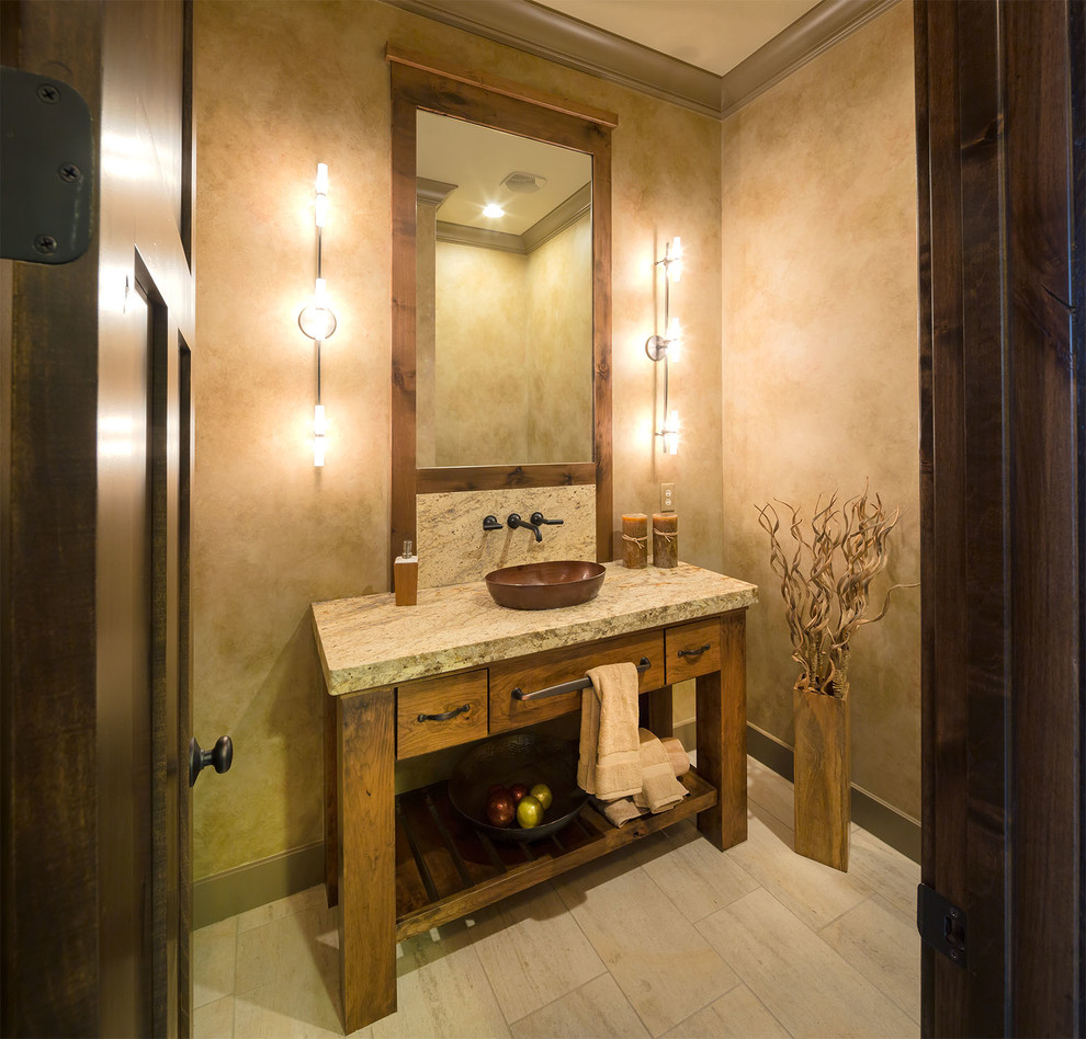 This is an example of a country powder room in Dallas with a vessel sink, furniture-like cabinets, medium wood cabinets, beige walls, beige floor and grey benchtops.