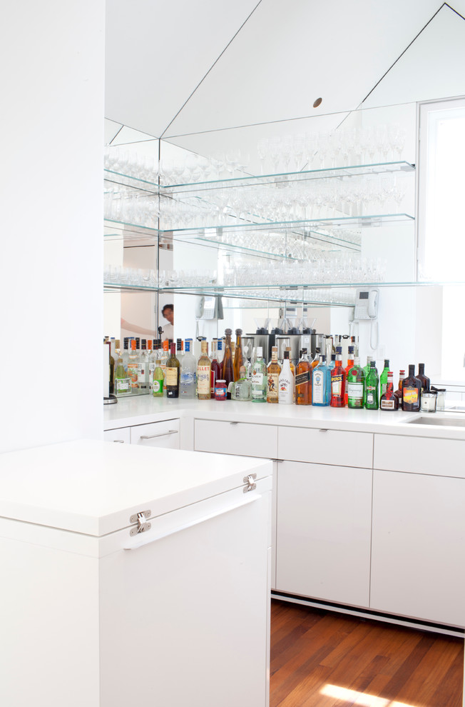 Design ideas for a mid-sized contemporary u-shaped wet bar in Boston with an undermount sink, flat-panel cabinets, white cabinets, dark hardwood floors and white benchtop.