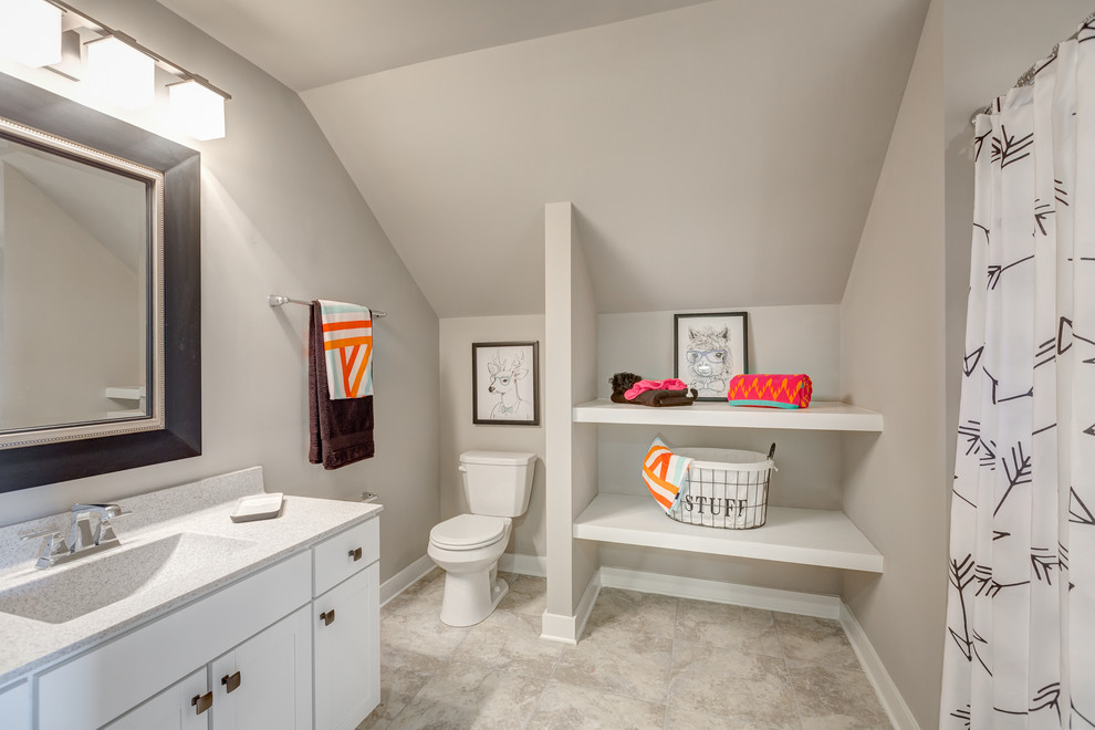 Mid-sized beach style kids bathroom in Other with recessed-panel cabinets, white cabinets, a shower/bathtub combo, a one-piece toilet, beige tile, grey walls, ceramic floors, an integrated sink and marble benchtops.