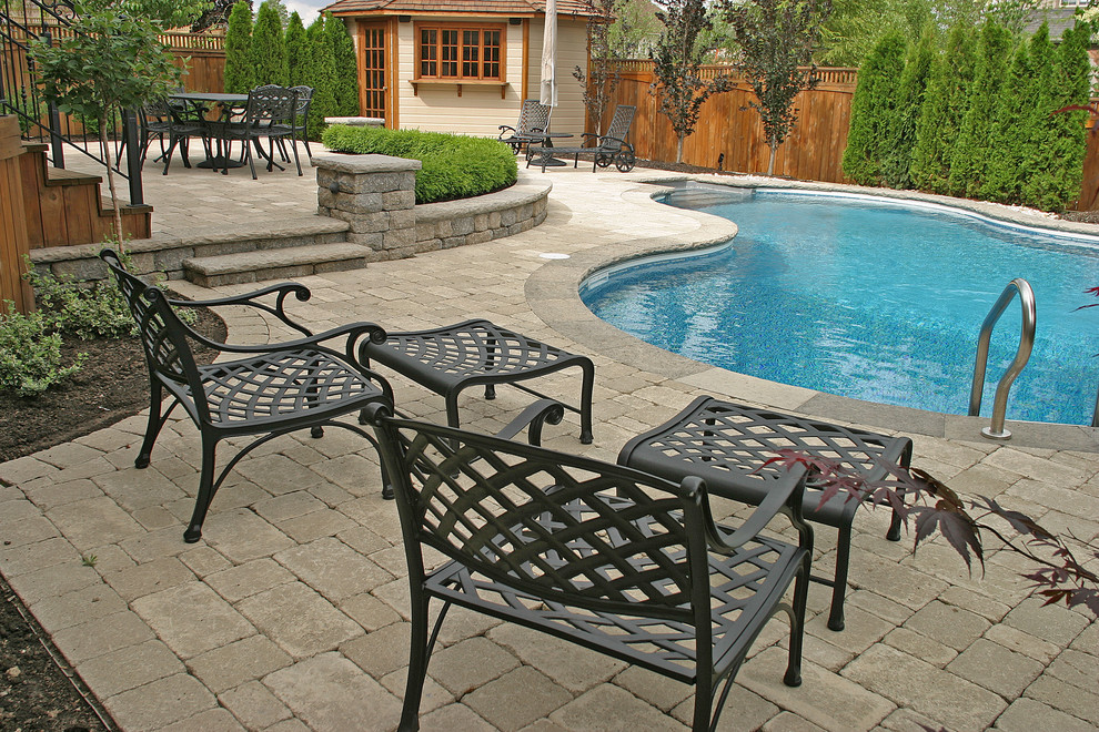 Mid-sized transitional backyard concrete paver and kidney-shaped partial sun and lap pool house photo for summer in Toronto