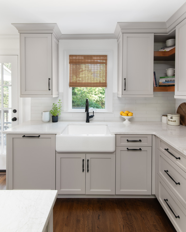 Eat-in kitchen - mid-sized transitional l-shaped medium tone wood floor and brown floor eat-in kitchen idea in New York with a farmhouse sink, shaker cabinets, beige cabinets, quartz countertops, white backsplash, porcelain backsplash, paneled appliances, an island and white countertops