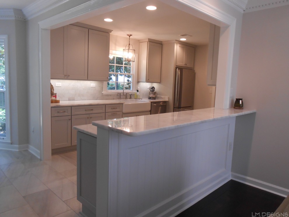 Inspiration for a transitional galley porcelain tile eat-in kitchen remodel with a farmhouse sink, recessed-panel cabinets, gray cabinets, marble countertops, stone tile backsplash, stainless steel appliances and a peninsula