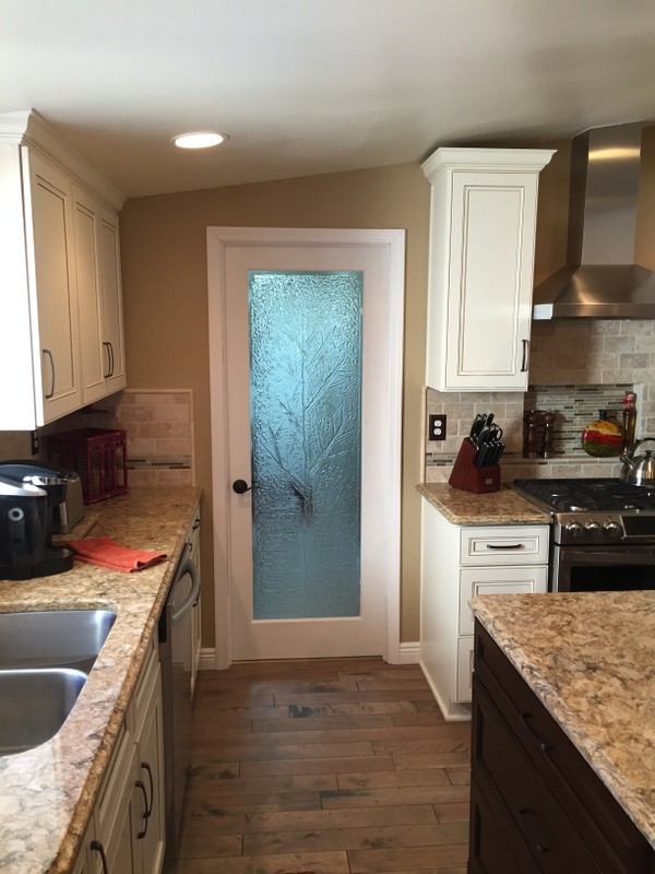 Example of a mid-sized transitional u-shaped medium tone wood floor eat-in kitchen design with an undermount sink, flat-panel cabinets, dark wood cabinets, quartz countertops, beige backsplash, stone tile backsplash, stainless steel appliances and an island