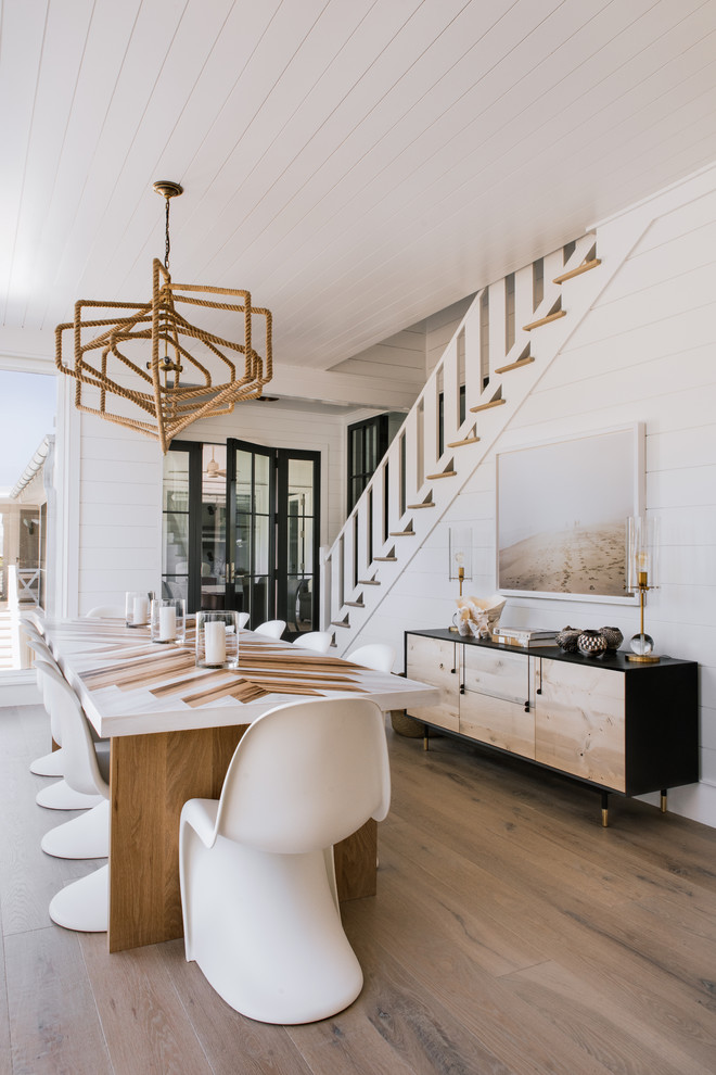 Photo of a beach style dining room in Charleston with white walls, light hardwood floors and beige floor.