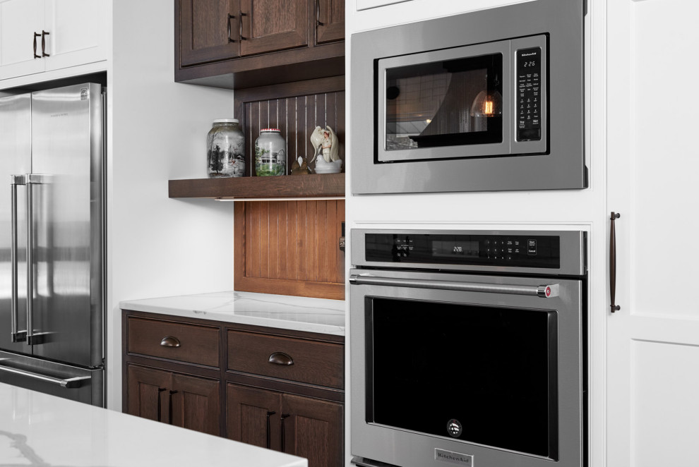 Enclosed kitchen - transitional galley light wood floor and brown floor enclosed kitchen idea in Toronto with a farmhouse sink, shaker cabinets, white cabinets, quartzite countertops, white backsplash, subway tile backsplash, stainless steel appliances, an island and white countertops