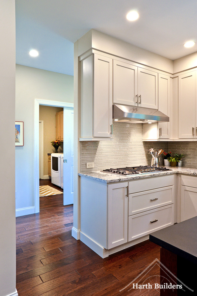 Eat-in kitchen - mid-sized transitional l-shaped medium tone wood floor eat-in kitchen idea in Philadelphia with an undermount sink, recessed-panel cabinets, white cabinets, granite countertops, gray backsplash, glass tile backsplash, stainless steel appliances and an island