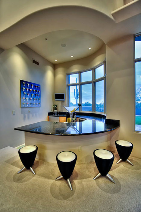 Design ideas for an expansive modern u-shaped seated home bar in Phoenix with a drop-in sink, flat-panel cabinets, medium wood cabinets, granite benchtops, black splashback, stone slab splashback and travertine floors.