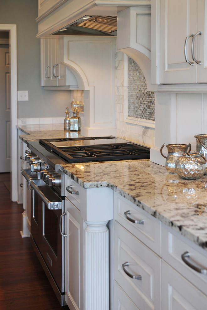 Mid-sized transitional l-shaped dark wood floor open concept kitchen photo with an undermount sink, raised-panel cabinets, white cabinets, granite countertops, white backsplash, mosaic tile backsplash, stainless steel appliances and an island