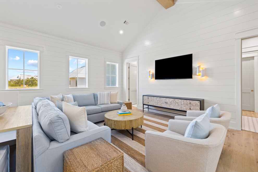 Immagine di un soggiorno stile marinaro con pareti bianche, parquet chiaro, TV a parete e pareti in perlinato
