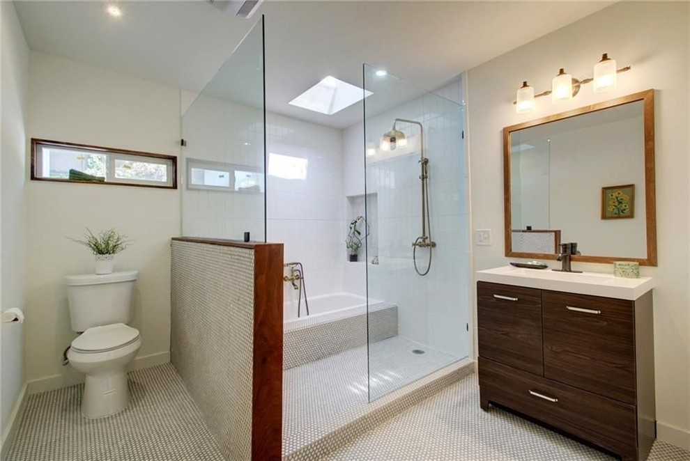 Design ideas for a large midcentury master bathroom in Austin with flat-panel cabinets, brown cabinets, a drop-in tub, a shower/bathtub combo, a two-piece toilet, white tile, pebble tile, white walls, cement tiles, an integrated sink, solid surface benchtops, white floor, a shower curtain and white benchtops.