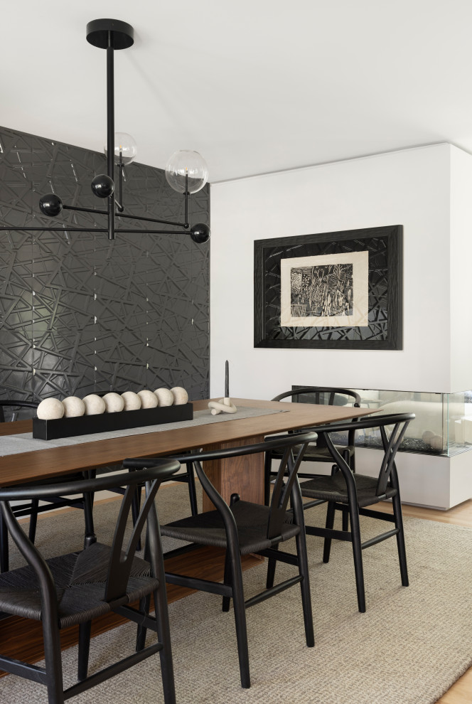 Photo of a mid-sized contemporary separate dining room in Denver with black walls, light hardwood floors, a two-sided fireplace, a plaster fireplace surround and panelled walls.