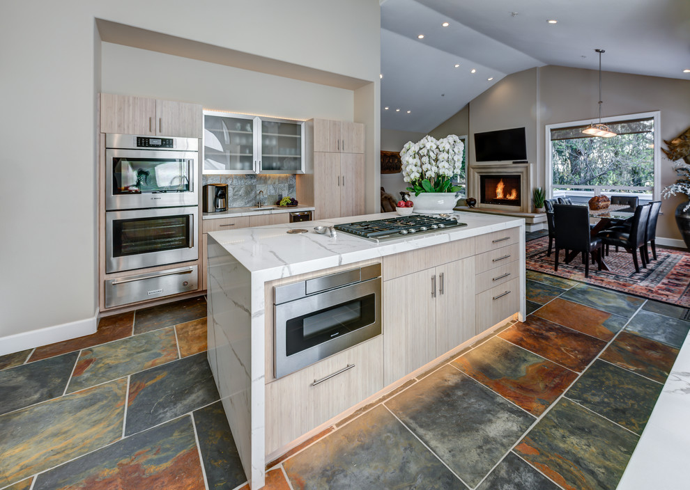 This is an example of a mid-sized contemporary l-shaped open plan kitchen in San Francisco with flat-panel cabinets, quartz benchtops, stainless steel appliances, with island, a single-bowl sink, light wood cabinets, slate floors, multi-coloured floor, multi-coloured splashback and slate splashback.