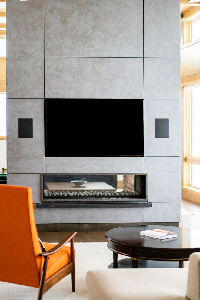 This is an example of a large contemporary open concept living room in Minneapolis with a two-sided fireplace, a concrete fireplace surround, a built-in media wall, beige walls, medium hardwood floors and brown floor.