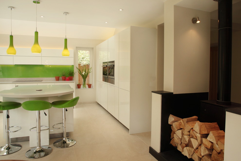 Large contemporary u-shaped kitchen in Buckinghamshire with an undermount sink, flat-panel cabinets, white cabinets, green splashback, glass sheet splashback and with island.