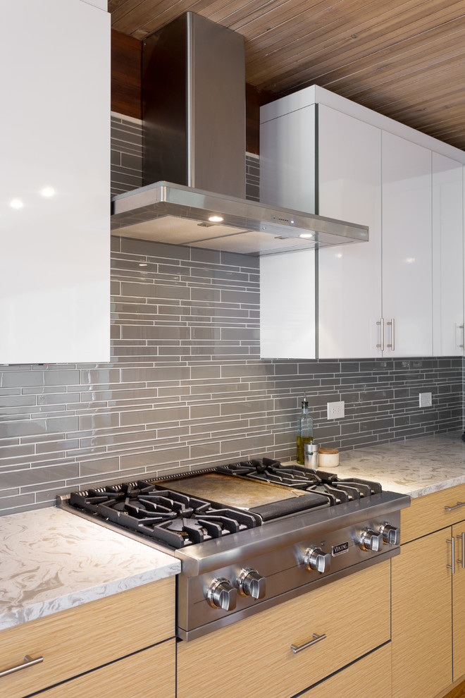 Inspiration for a large modern l-shaped open plan kitchen in Chicago with flat-panel cabinets, white cabinets, marble benchtops, grey splashback, stainless steel appliances, medium hardwood floors, with island, subway tile splashback and an undermount sink.