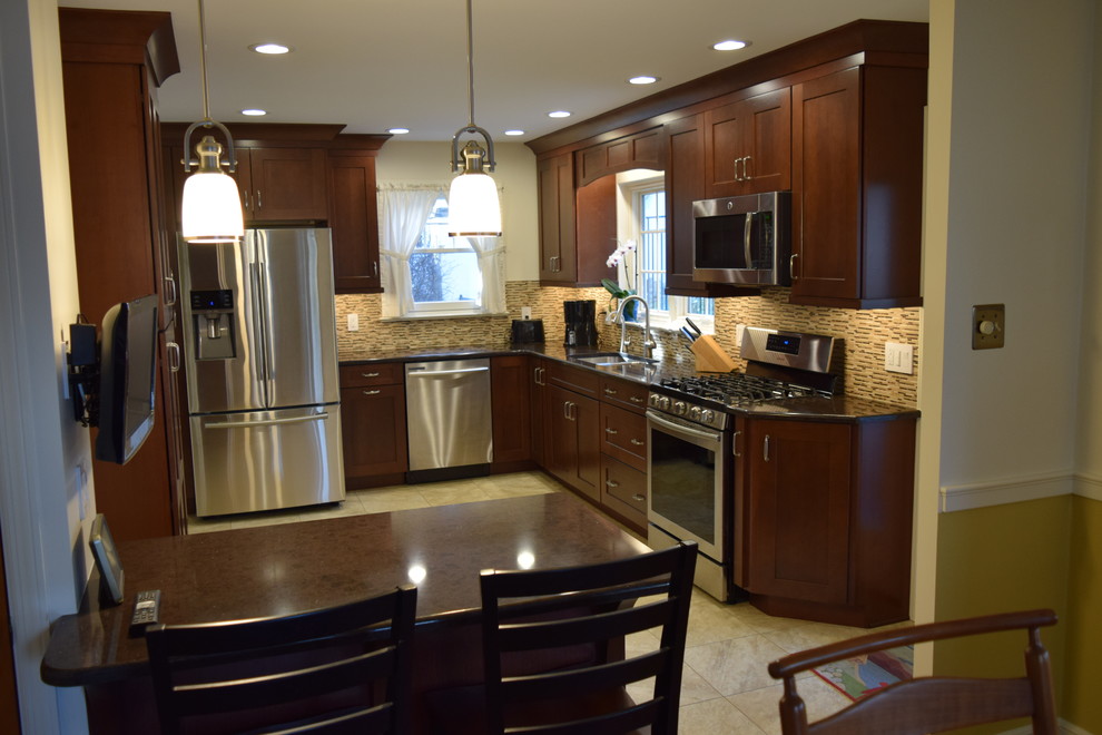 Transitional l-shaped vinyl floor and beige floor kitchen photo with an undermount sink, shaker cabinets, medium tone wood cabinets, quartz countertops, beige backsplash, glass tile backsplash, stainless steel appliances and a peninsula