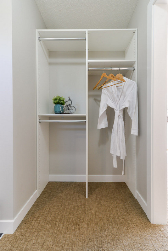 Design ideas for a small contemporary gender-neutral walk-in wardrobe in Calgary with white cabinets and carpet.