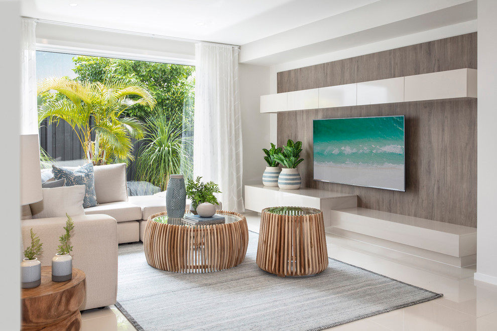 This is an example of a beach style living room in Brisbane with white walls, a wall-mounted tv and white floor.
