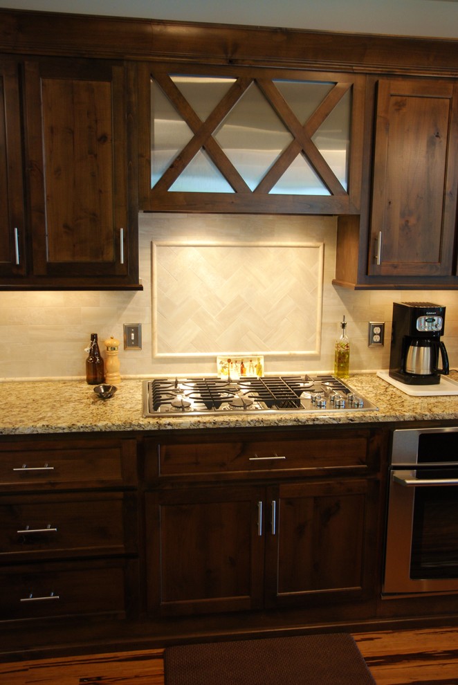 This is an example of a mid-sized traditional galley open plan kitchen in Atlanta with an undermount sink, recessed-panel cabinets, dark wood cabinets, granite benchtops, white splashback, ceramic splashback, stainless steel appliances, bamboo floors, multiple islands and brown floor.