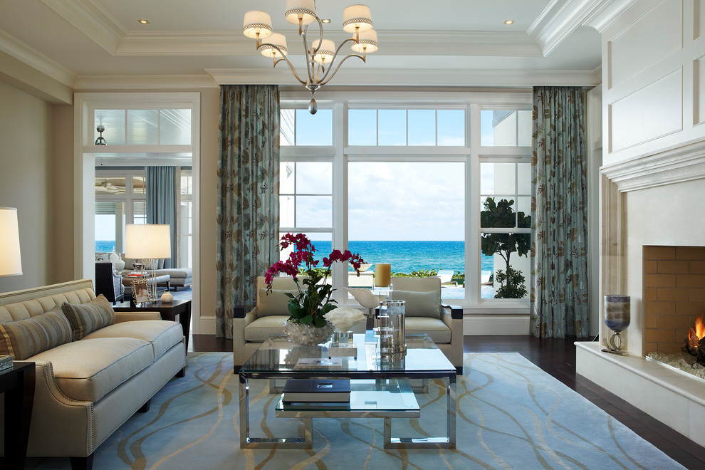 This is an example of an expansive beach style formal open concept living room in Miami with beige walls, dark hardwood floors, a standard fireplace, a stone fireplace surround and no tv.