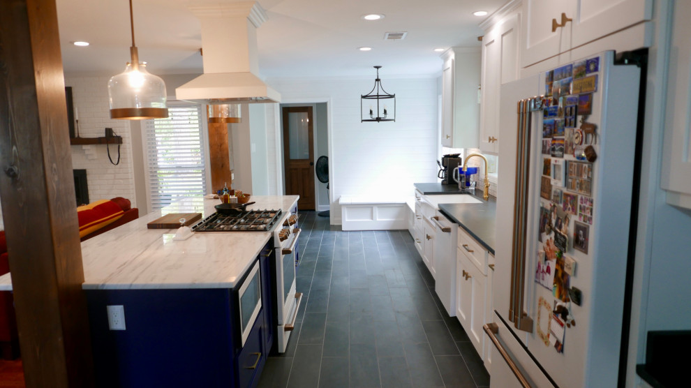 Mid-sized transitional galley porcelain tile and black floor eat-in kitchen photo with a farmhouse sink, shaker cabinets, white cabinets, marble countertops, white backsplash, subway tile backsplash, white appliances, an island and multicolored countertops