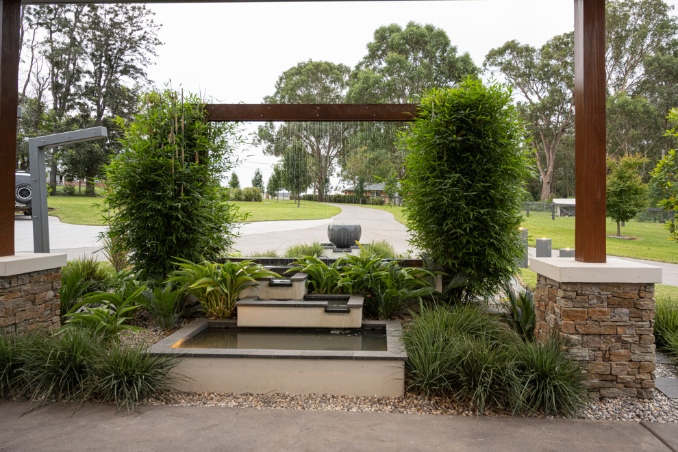 Photo of an expansive tropical front yard driveway in Sydney.