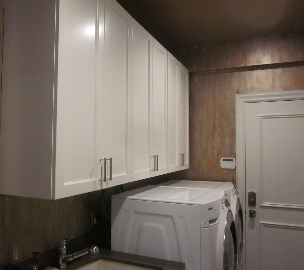 This is an example of a small contemporary galley dedicated laundry room in New York with a drop-in sink, recessed-panel cabinets, white cabinets, granite benchtops, beige walls, dark hardwood floors and a side-by-side washer and dryer.