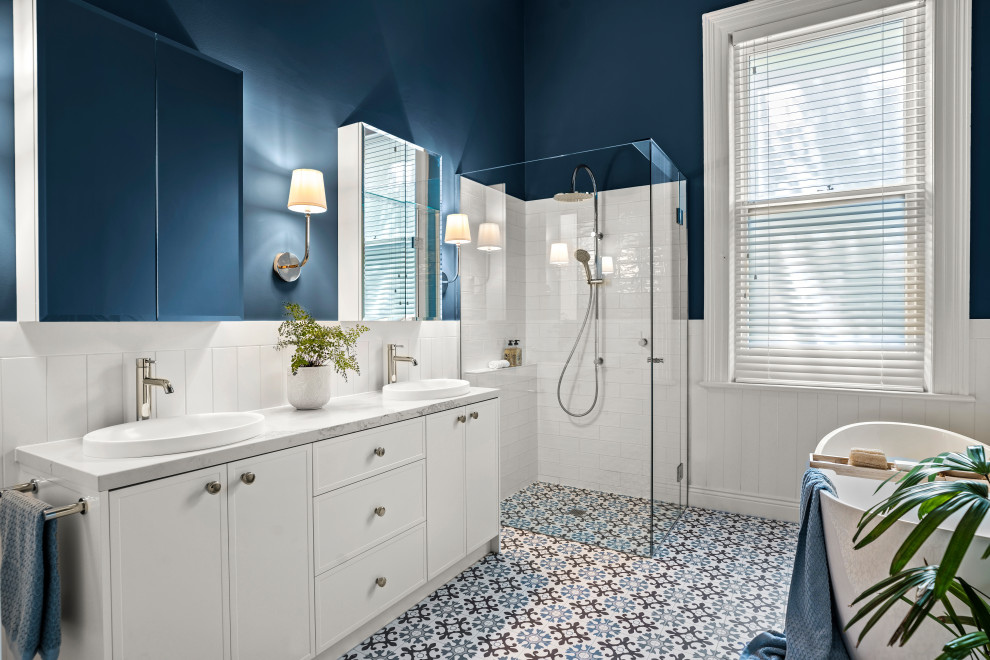 Photo of a large traditional 3/4 bathroom in Melbourne with shaker cabinets, white cabinets, a freestanding tub, a curbless shower, white tile, ceramic tile, blue walls, porcelain floors, a drop-in sink, engineered quartz benchtops, a hinged shower door, white benchtops, a double vanity, a freestanding vanity and panelled walls.