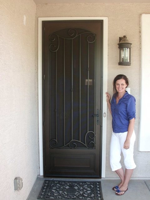 Large mountain style concrete floor front door photo in Phoenix with beige walls and a black front door