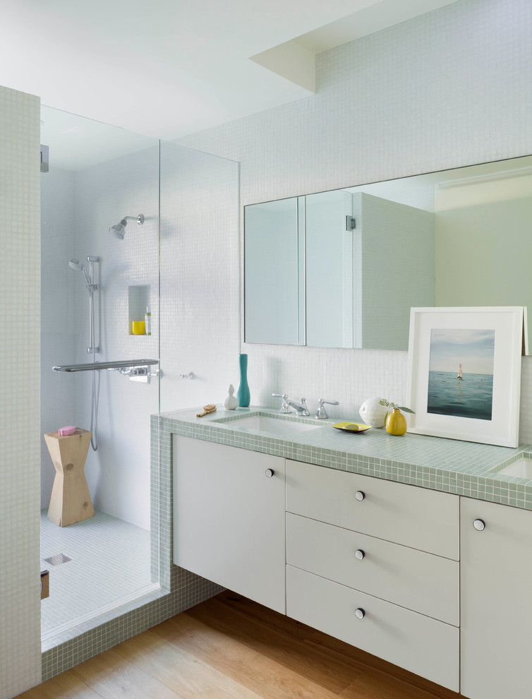 Inspiration for a small contemporary master bathroom in Los Angeles with an undermount sink, flat-panel cabinets, green cabinets, tile benchtops, an undermount tub, an open shower, a one-piece toilet, green tile, glass tile, white walls and light hardwood floors.