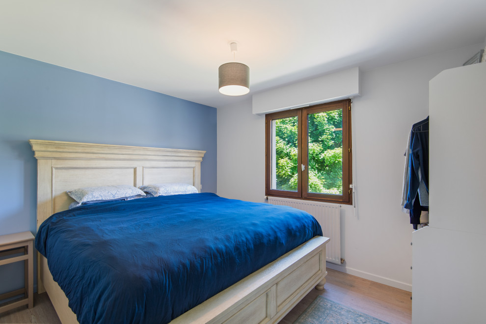 Photo of a mid-sized country master bedroom in Other with blue walls, laminate floors and beige floor.