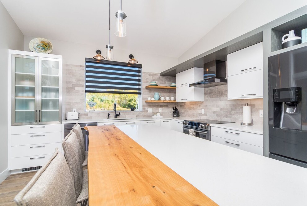 Large transitional l-shaped light wood floor and brown floor kitchen photo with an undermount sink, flat-panel cabinets, white cabinets, quartz countertops, brown backsplash, subway tile backsplash, stainless steel appliances and an island