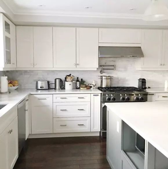 Photo of a mid-sized modern galley kitchen pantry in Raleigh with an integrated sink, white cabinets, marble benchtops, white splashback, white appliances, laminate floors, brown floor and white benchtop.