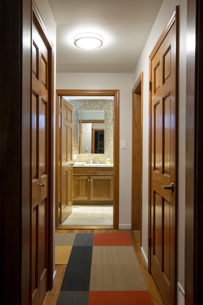 This is an example of a small transitional hallway in New York with white walls, medium hardwood floors and brown floor.