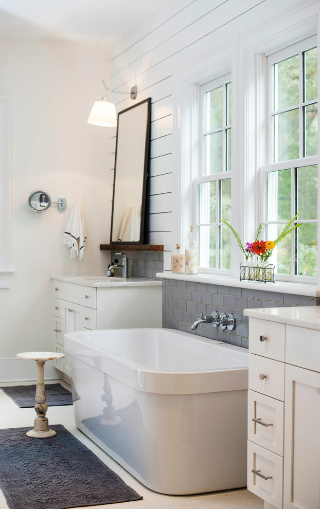 Design ideas for a country master bathroom in Charlotte with an undermount sink, white cabinets, a freestanding tub, gray tile and subway tile.