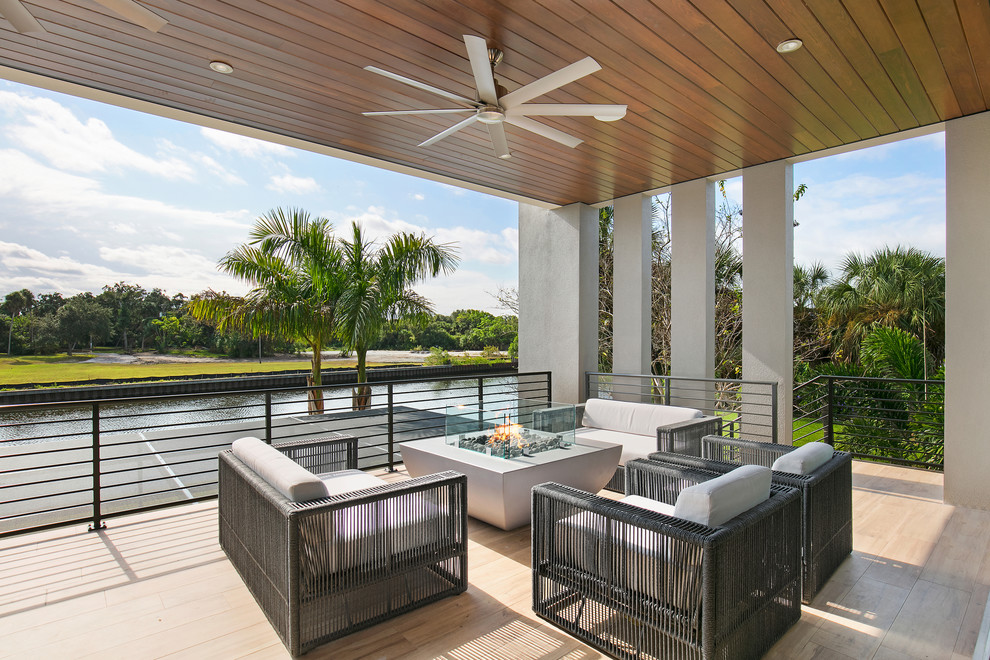 Photo of a mid-sized contemporary deck in Tampa with a fire feature, a roof extension and metal railing.