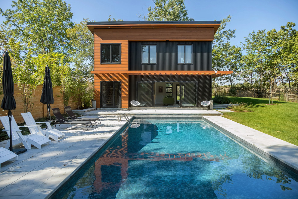 Photo of a medium sized rustic back rectangular swimming pool in Toronto with a pool house.