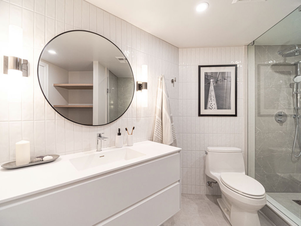 Exemple d'une douche en alcôve principale moderne de taille moyenne avec un placard à porte plane, des portes de placard blanches, WC à poser, un carrelage blanc, des carreaux de céramique, un mur blanc, un sol en carrelage de céramique, un lavabo intégré, un sol gris, une cabine de douche à porte battante, un plan de toilette blanc, meuble simple vasque et meuble-lavabo suspendu.