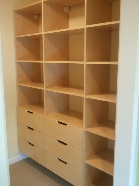 Photo of a mid-sized contemporary gender-neutral walk-in wardrobe in Other with flat-panel cabinets, light wood cabinets and carpet.