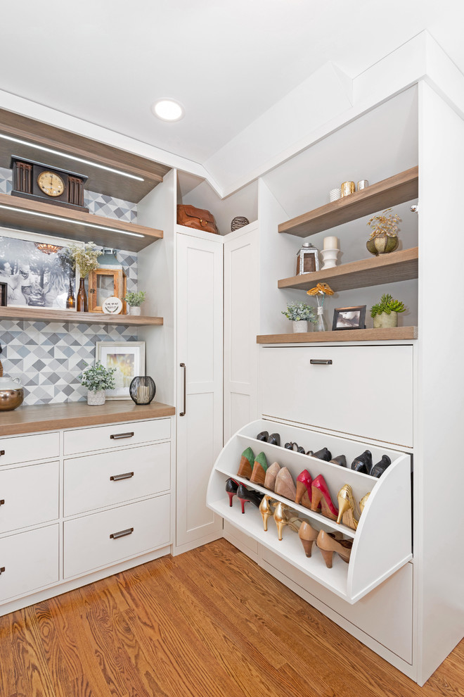 Photo of a large transitional gender-neutral walk-in wardrobe in Other with white cabinets, medium hardwood floors, shaker cabinets and brown floor.