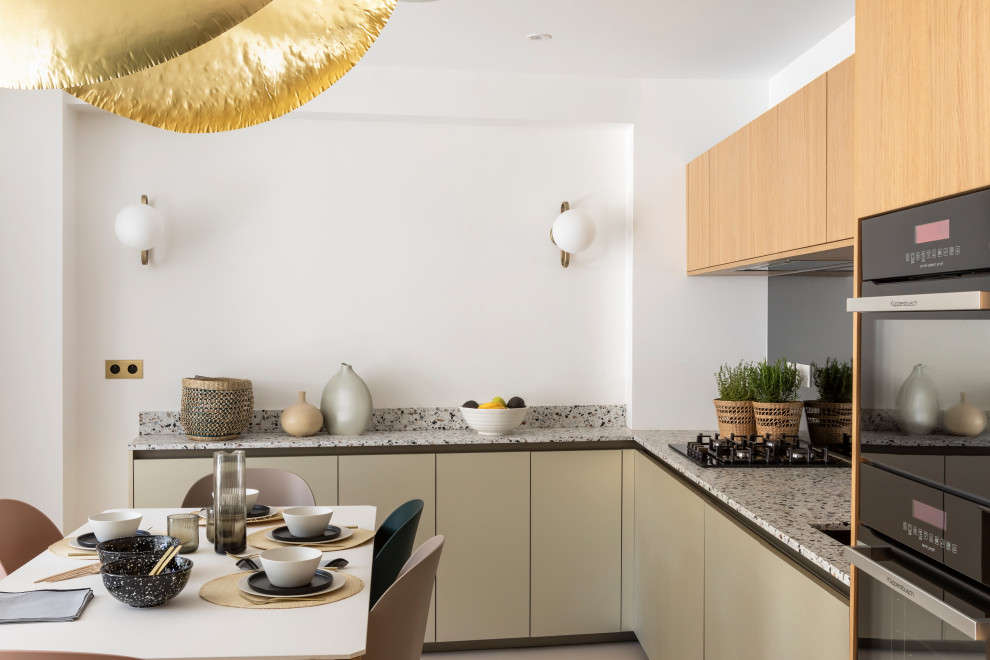 Photo of a mid-sized contemporary l-shaped open plan kitchen in Paris with an undermount sink, beaded inset cabinets, light wood cabinets, terrazzo benchtops, metallic splashback, mirror splashback, panelled appliances, concrete floors and beige floor.