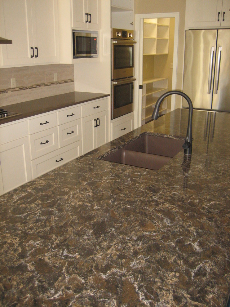 Open concept kitchen - mid-sized transitional l-shaped dark wood floor open concept kitchen idea with an undermount sink, recessed-panel cabinets, white cabinets, quartz countertops, beige backsplash, ceramic backsplash, stainless steel appliances and an island