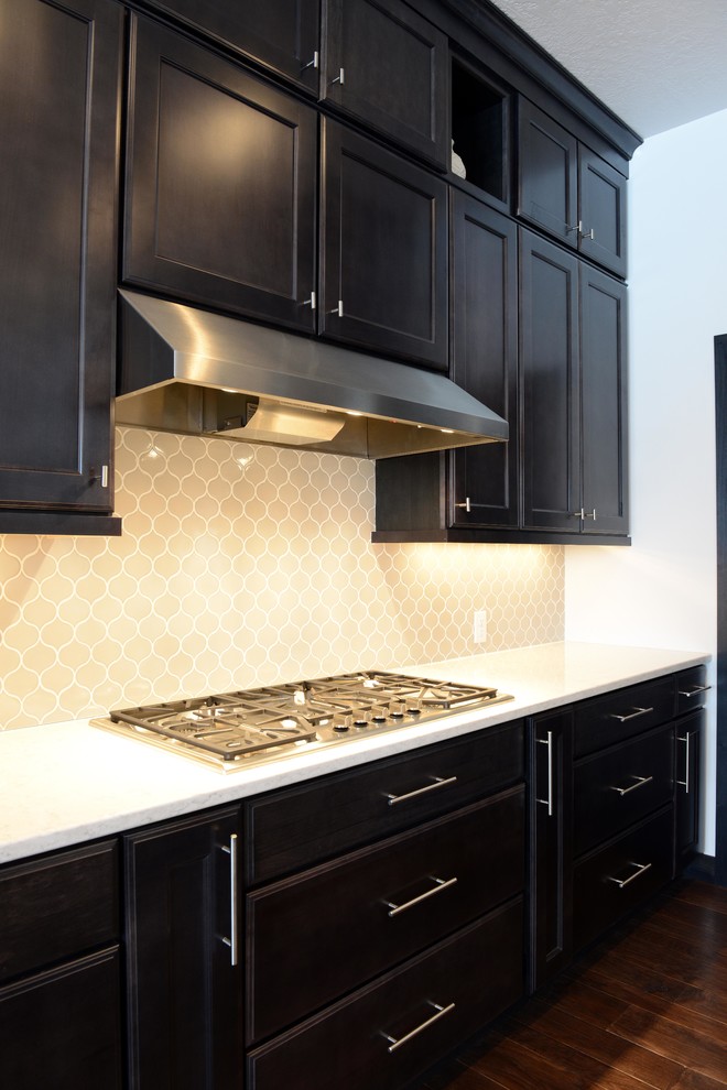 Example of a large transitional l-shaped medium tone wood floor open concept kitchen design with an undermount sink, shaker cabinets, dark wood cabinets, quartz countertops, gray backsplash, porcelain backsplash, stainless steel appliances and an island