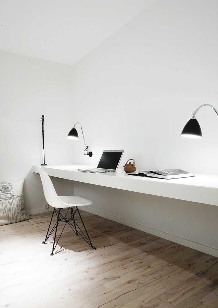 This is an example of a mid-sized scandinavian study room in Copenhagen with white walls, medium hardwood floors, no fireplace and a built-in desk.