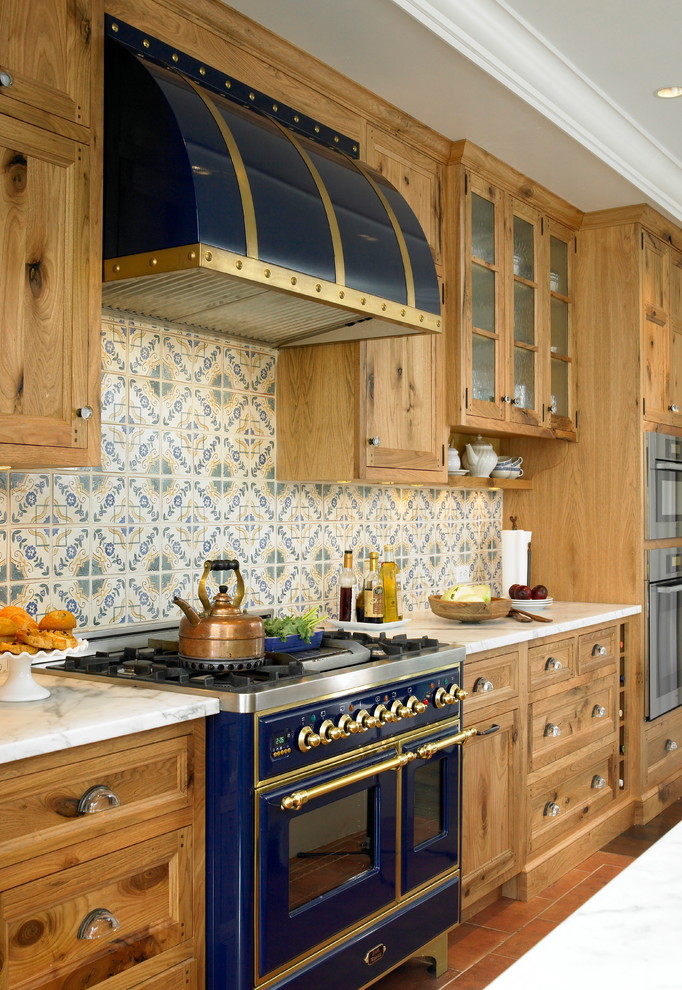 Inspiration for a large mediterranean terra-cotta tile kitchen remodel in New York with recessed-panel cabinets, medium tone wood cabinets, multicolored backsplash and colored appliances