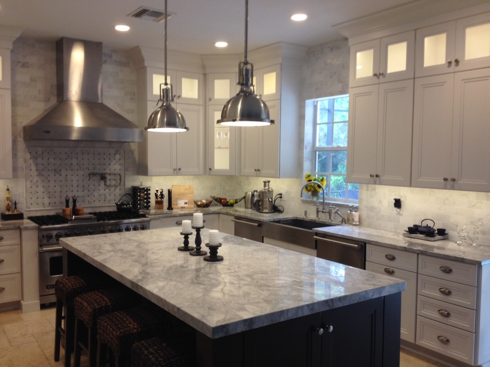 This is an example of a large traditional u-shaped kitchen in Miami with a farmhouse sink, recessed-panel cabinets, white cabinets, marble benchtops, white splashback, stainless steel appliances, travertine floors, with island, stone tile splashback and beige floor.